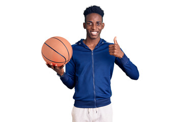 Obraz premium Young african american man holding basketball ball smiling happy and positive, thumb up doing excellent and approval sign