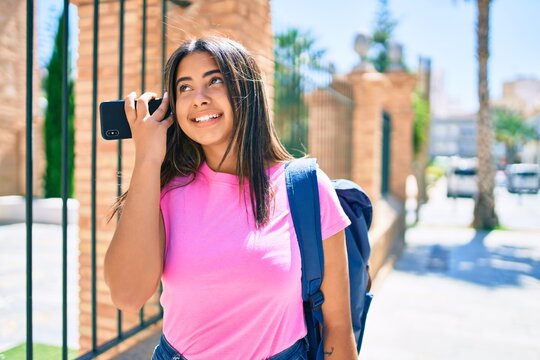 Young latin student girl listening audio message using smartphone at university campus.