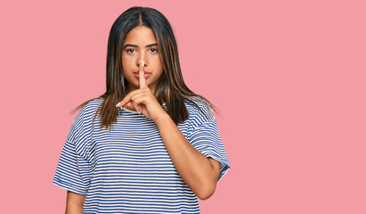 Young latin girl wearing casual clothes asking to be quiet with finger on lips. silence and secret...