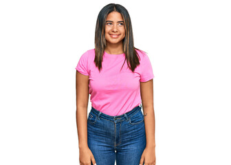 Obraz premium Young latin girl wearing casual clothes looking away to side with smile on face, natural expression. laughing confident.