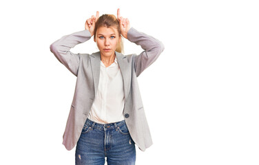 Fototapeta premium Young beautiful blonde woman wearing elegant jacket doing funny gesture with finger over head as bull horns