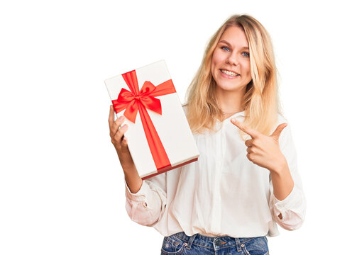 Young beautiful blonde woman holding gift pointing finger to one self smiling happy and proud