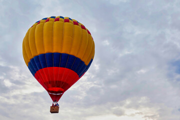 Striped yellow blue red balloon against cloudy sky