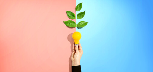 Person holding a light bulbs with green leaves