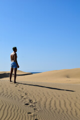 Fototapeta na wymiar Man in swimming trunks walking through the desert sand dunes.
