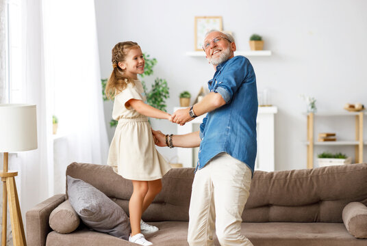 Grandfather dancing with granddaughter at home.