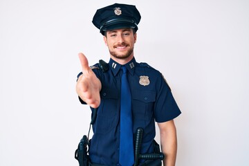 Young caucasian man wearing police uniform smiling cheerful offering palm hand giving assistance...