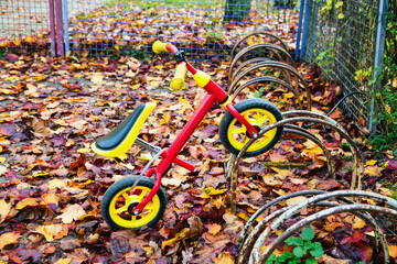 close-up of kids tricycle at bicycle stand in autumn