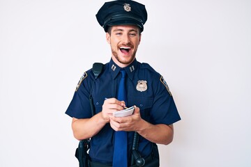 Young caucasian man wearing police uniform writing fine smiling and laughing hard out loud because...