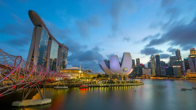 Downtown skyline of Singapore as viewed from across the water from The Garden East day to night transition time lapse. Singapore. Reflection in water with illuminated skyscrapers