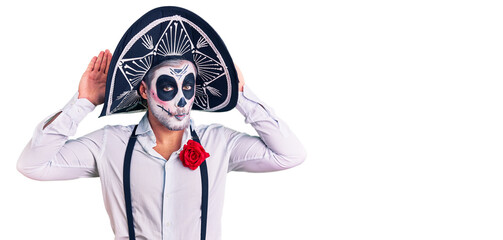 Man wearing day of the dead costume over background doing bunny ears gesture with hands palms looking cynical and skeptical. easter rabbit concept.