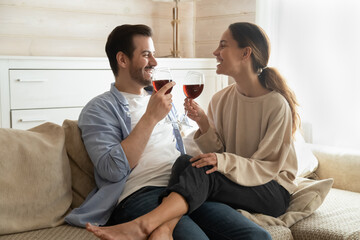 Romantic evening. Affectionate happy millennial family couple sitting on couch at modern living...