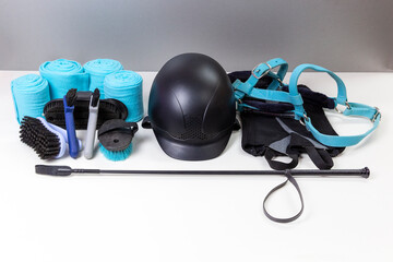 Flat lay of equestrian gear: helmet, brushes, whip, bandages, stirrups, pads, dressage, bridle. Accessories and equipment for horse care and riding
