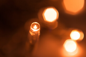 A blurry background of small yellow lanterns on a thin garland burns with a gentle light in a...