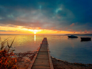 Magic sunrise on the lake. Late fall. Pier going into the horizon