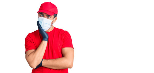 Young hispanic man wearing covid-19 safety mask thinking looking tired and bored with depression problems with crossed arms.