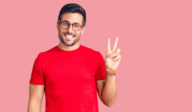Young hispanic man wearing casual clothes and glasses smiling with happy face winking at the camera doing victory sign. number two.