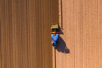 Luftaufnahme auf einen blauen Traktor beim Umpflügen eines Ackers hinterläßt Spuren auf dem Feld © reisezielinfo