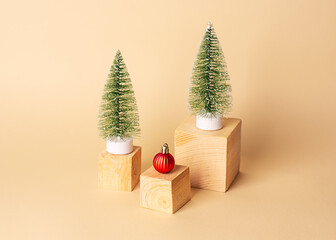 New year creative concept. Two artificial Christmas trees, red Christmas decoration on wooden cubes on a beige background. Christmas background.Minimal New Year decoration concept. Copy spase