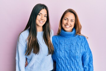 Hispanic family of mother and daughter wearing wool winter sweater with a happy and cool smile on face. lucky person.