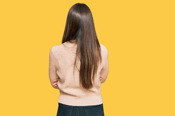 Young brunette woman wearing casual winter sweater standing backwards looking away with crossed arms