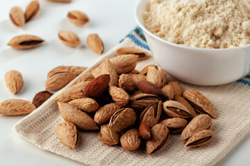 Almond nuts and almond flour in a plate are on a white table