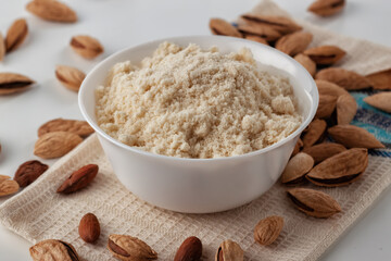 Almond nuts and almond flour in a plate are on a white table