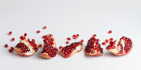 slices of pomegranate isolated, pomegranate grains scattered on white background