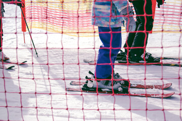 Obraz premium ski resort, children and adults on skis in line for the uphill ski lift