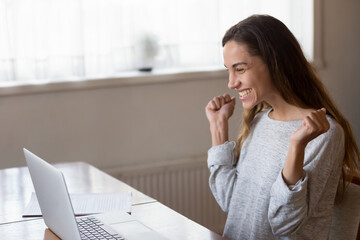 I am lucky. Overjoyed excited millennial female student teleworker enterpreneur feeling happy reading email message with good news at laptop screen, glad winning money valuable prize at online lottery