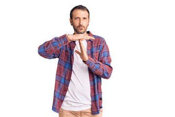 Young handsome man wearing casual clothes doing time out gesture with hands, frustrated and serious...