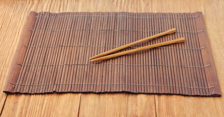 Sushi sticks on brown bamboo food placemat on wooden table takencloseup.
