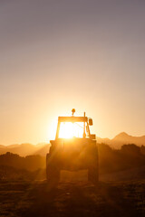 tractor stopped at sunset after workday. the sun breaks through the cabin. concept of industry and...