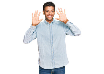 Young handsome african american man wearing casual clothes showing and pointing up with fingers number ten while smiling confident and happy.