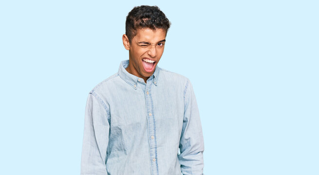 Young handsome african american man wearing casual clothes winking looking at the camera with sexy expression, cheerful and happy face.