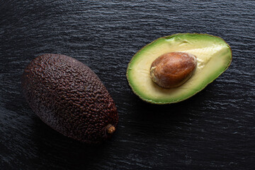 whole and cut ripe avocado lie on the board