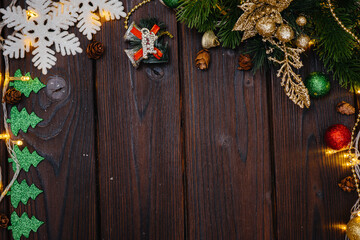 The wooden Christmas background is decorated with festive decor, lanterns, snowflakes and branches of the Christmas tree. Christmas card. Winter holiday season. Happy New Year.