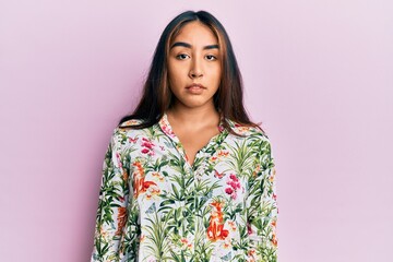 Young latin woman wearing casual clothes with serious expression on face. simple and natural looking at the camera.