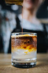 Adding coffee to a glass with ice and lime tonic - iced coffee