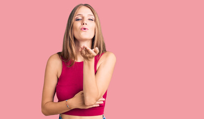 Young beautiful blonde woman wearing elegant summer shirt looking at the camera blowing a kiss with hand on air being lovely and sexy. love expression.