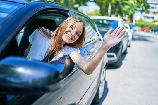 Young beautiful blonde woman smiling happy sitting at the car with hand out and cheerful expression