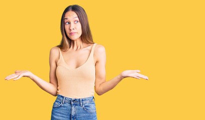 Beautiful brunette young woman wearing casual clothes clueless and confused expression with arms...