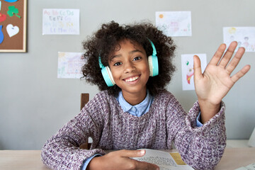 Happy african american kid child girl wearing headphones waving hand talking with remote teacher on social distance learning video conference call chat class, headshot zoom portrait, web cam view. - Powered by Adobe