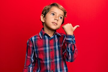 Adorable latin kid wearing casual clothes pointing thumb up to the side smiling happy with open mouth