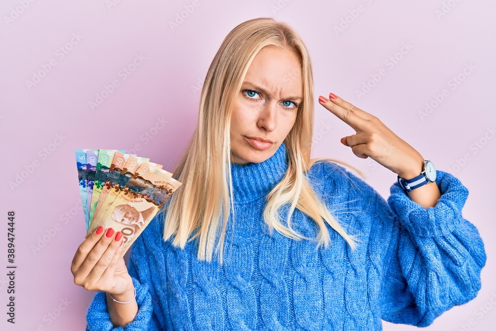 Canvas Prints young blonde girl holding canadian dollars shooting and killing oneself pointing hand and fingers to