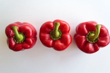 Top view of three red peppers in line on white background