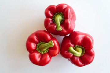 Top view of three red peppers on white background