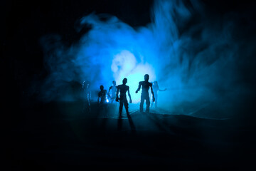 Fototapeta premium Scary view of zombies at cemetery dead tree, moon, church and spooky cloudy sky with fog, Horror Halloween concept with glowing pumpkin. Selective focus