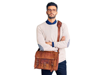 Young handsome hispanic man wearing leather bag skeptic and nervous, disapproving expression on face with crossed arms. negative person.