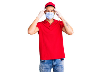 Fototapeta na wymiar Young handsome hispanic man wearing delivery uniform and medical mask suffering from headache desperate and stressed because pain and migraine. hands on head.